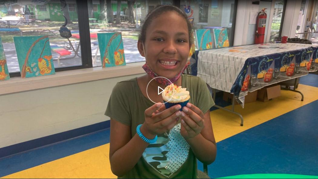 Screenshot of video featuring Shanella Fisher, age 11, holding a cupcake and smiling during her birthday party